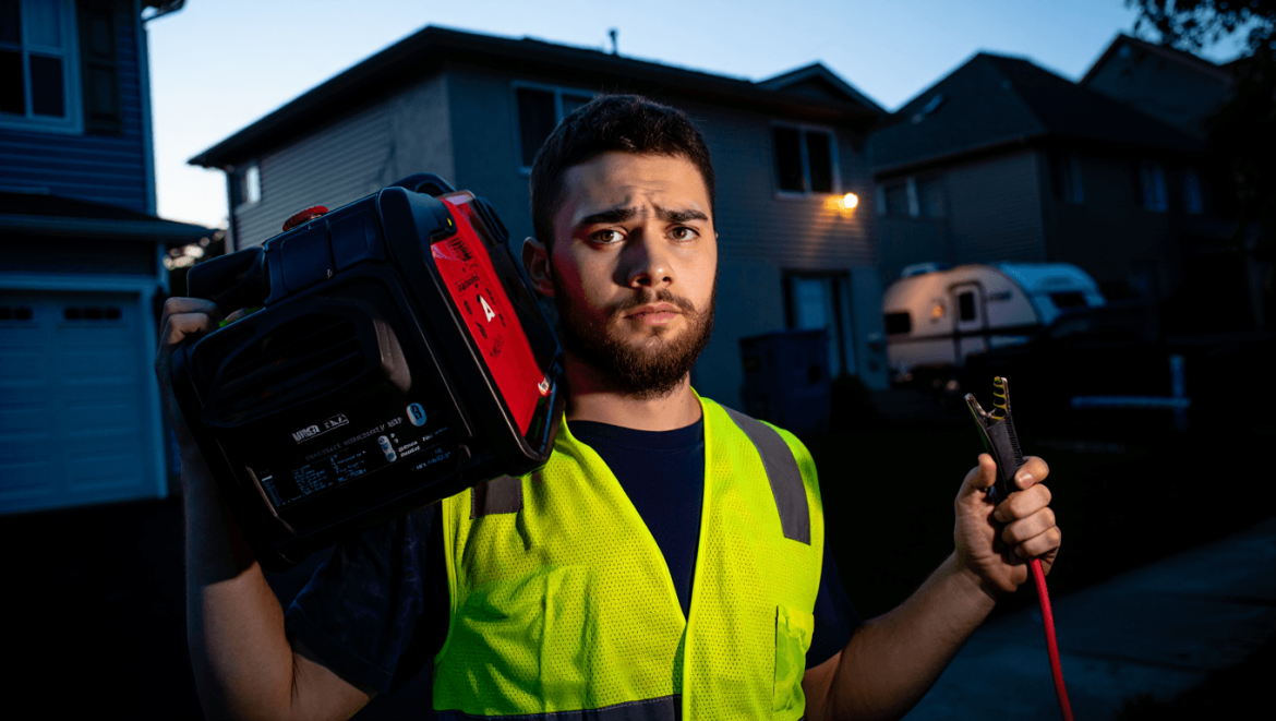 Un groupe électrogène posé sur le gazon avec une femme et un homme en fond