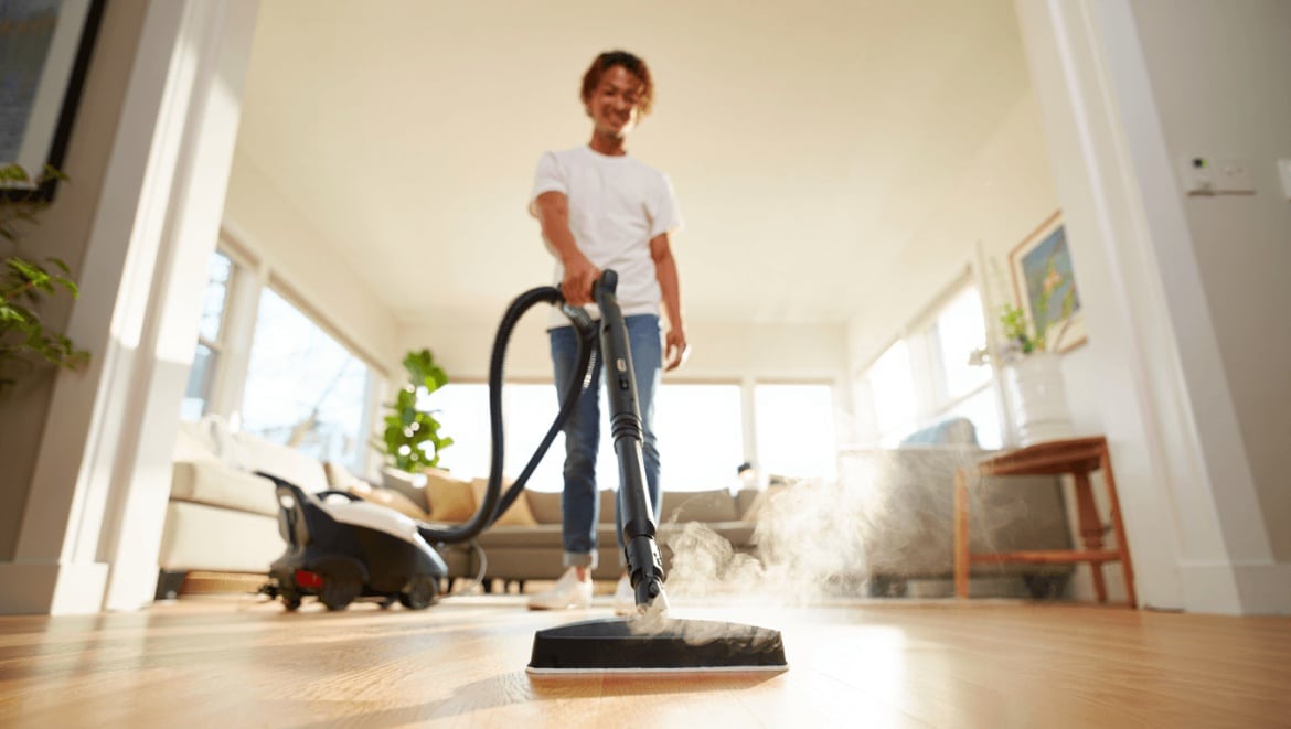 Une personne nettoie le canapé avec un nettoyeur à vapeur