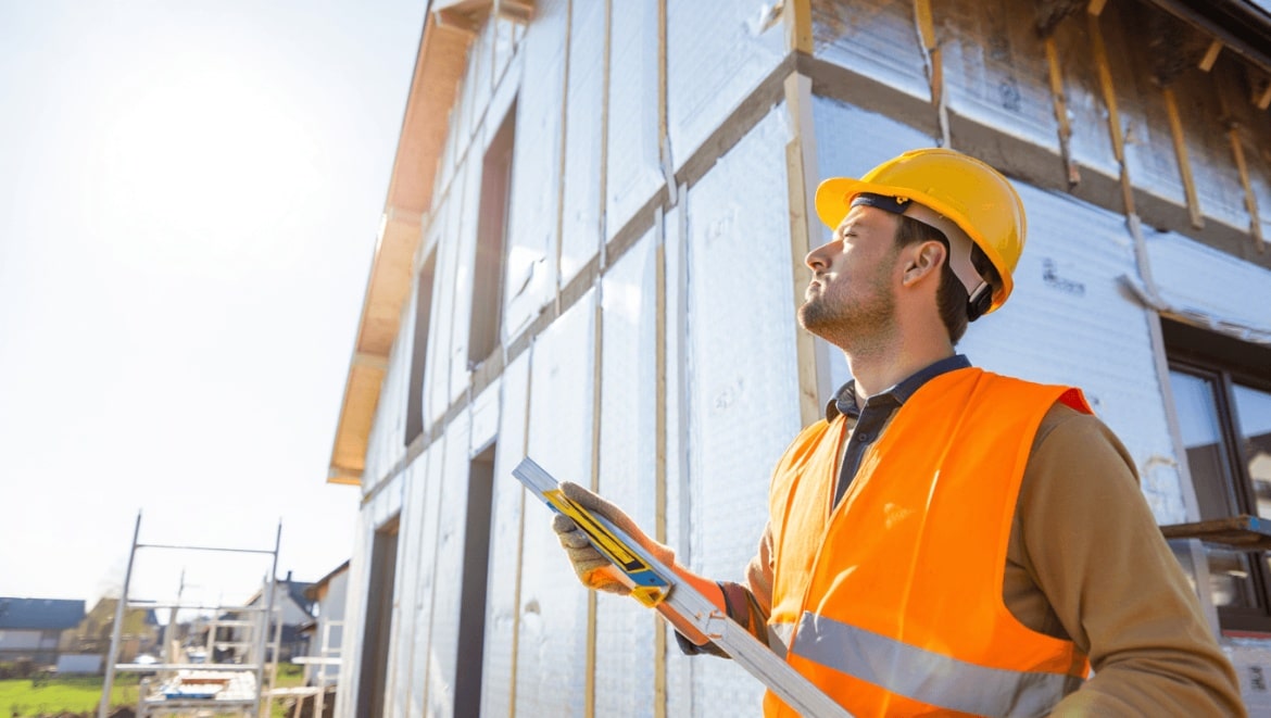 Zoom sur la main d'un homme tenant un crayon et dessinant le plan d'isolation thermique d'une maison