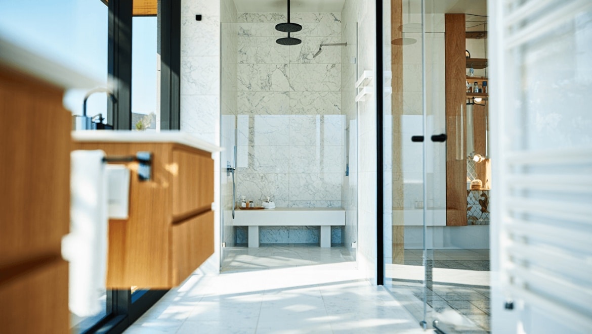 Une salle de bains grise avec grande douche à l'italienne en verre