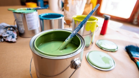 Différents pots de peinture et pinceaux sur une table en bois