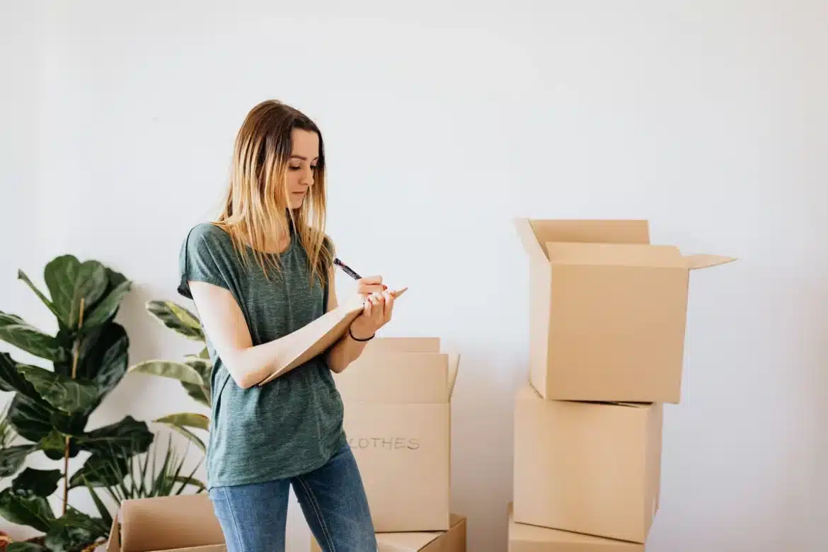 Mains tenant une liste de contrôle et un appareil photo dans un appartement vide bien éclairé