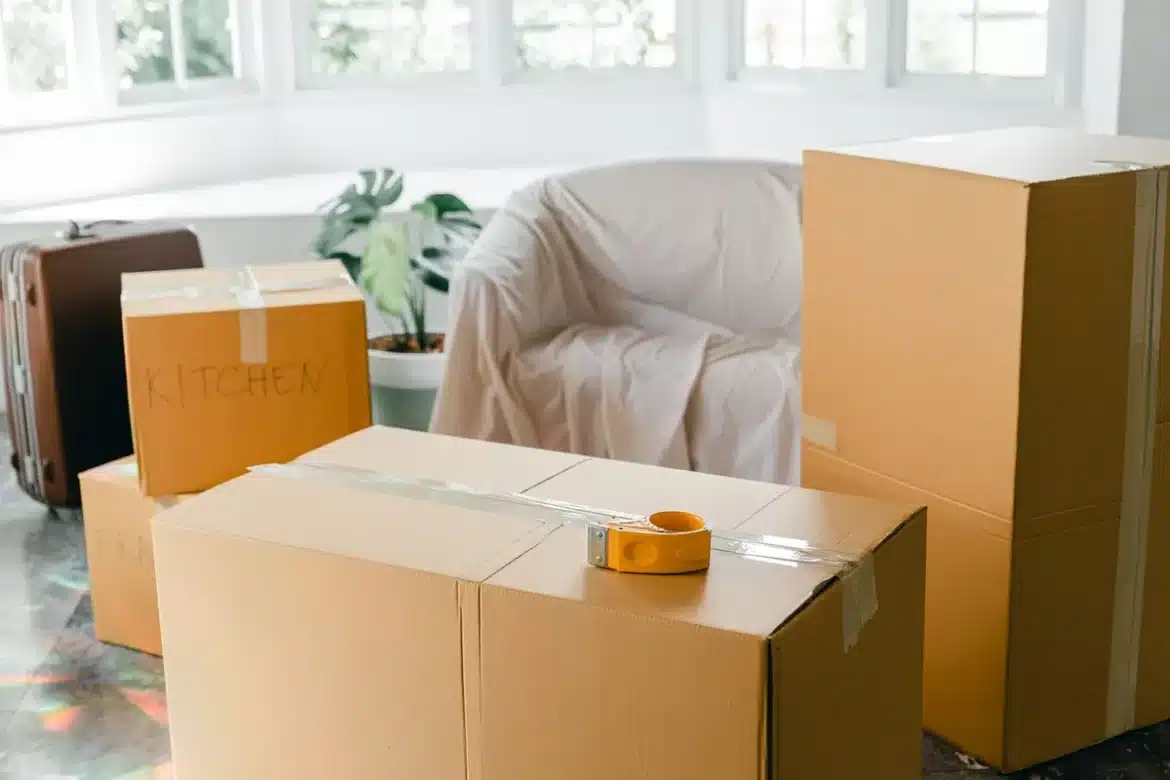 Mains anonymes emballant des cartons de déménagement dans un salon organisé
