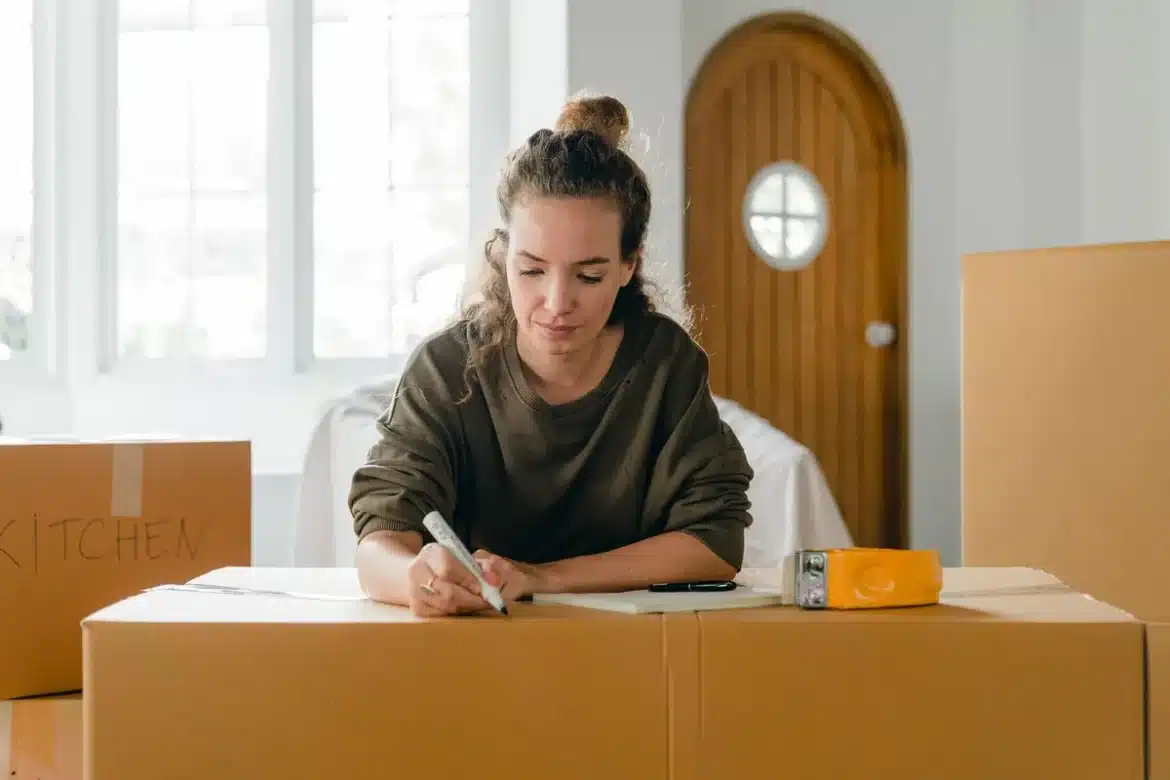 Mains tenant des cartons de déménagement et des documents administratifs sur une table