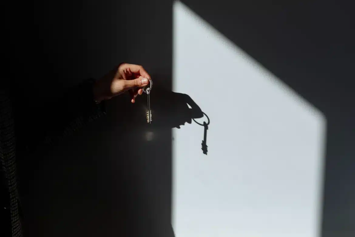 Mains tenant des clés de logement au-dessus d'un contrat de location avec documents et calculatrice