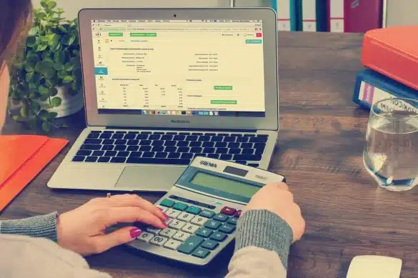 Mains tenant un document de régularisation des charges locatives et une calculatrice sur un bureau