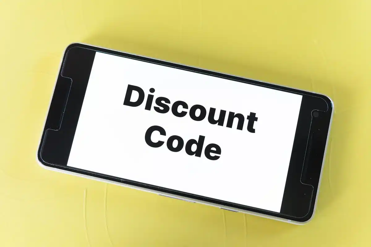 Personne utilisant un ordinateur pour faire des achats en ligne avec codes promo