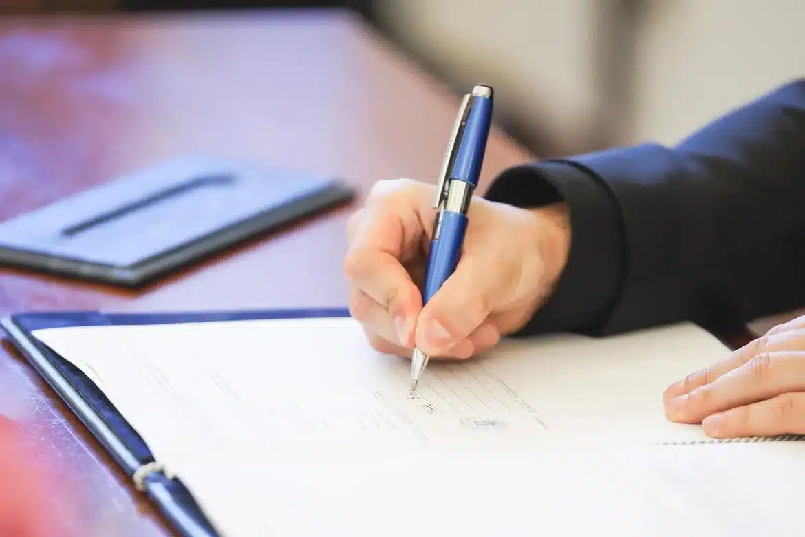 Dossier de location et documents triés sur une table près d'une fenêtre en plein jour